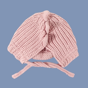 Detailed knit texture and tie strings of a pink baby bonnet dinosaur knit hat for winter