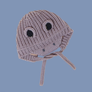 Detail of greyish-purple knitted dinosaur baby hat with funny eyes and chin straps