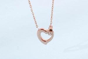Close-up of rose gold hollow heart necklace with a single diamond-set small ring detail