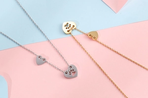 Dettaglio di ciondoli a cuore traforati con impronte di zampe in oro e argento