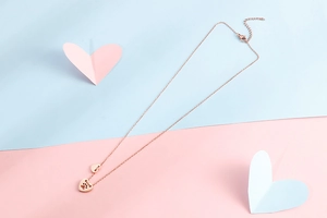 Dettaglio della collana in oro rosa con doppi ciondoli a cuore e impronta di zampa intagliata