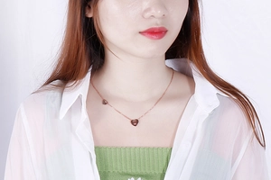 Primo piano di una collana a cuore oro rosa con impronta di zampa su una modella