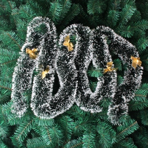 Détail d'une guirlande de Noël vert foncé de 2m avec pointes blanches et nœuds dorés