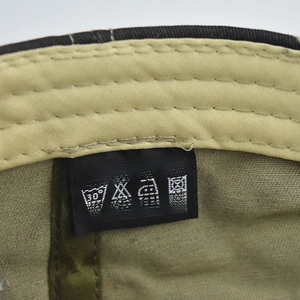 Macro shot of 100% cotton material tag and washing symbols on the green baseball cap