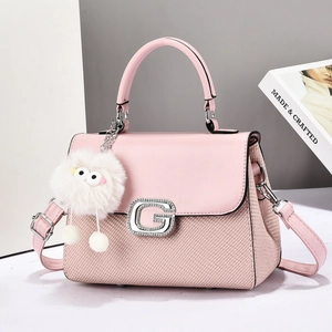 Pink crossbody bag with G buckle and plush charm on a fashion magazine background