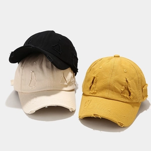 Close-up of distressed vintage baseball caps in black, beige, and mustard yellow colors