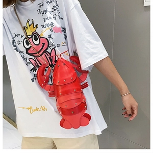 Detail of red lobster-shaped crossbody bag featuring gold studs and chain strap on model