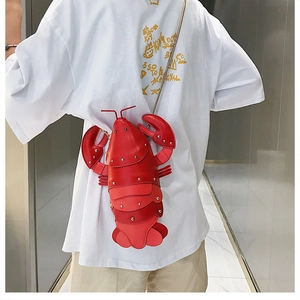 Close-up of a creative red lobster crossbody bag with silver studs and golden chain