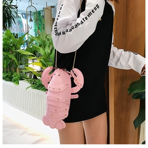 Pink lobster-shaped crossbody bag with gold rivets and chain strap on a model