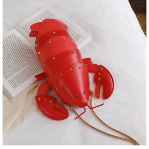 Close-up of red lobster-shaped crossbody bag with gold chain and rivet details