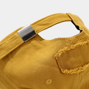 Detail of distressed baseball cap rear metal buckle and vintage mustard yellow cotton fabric