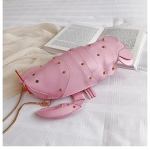 Detail of pink leather lobster bag showing golden rivet accents and metallic snake chain