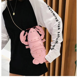 Detail of pink lobster crossbody bag with gold rivets and metallic chain strap