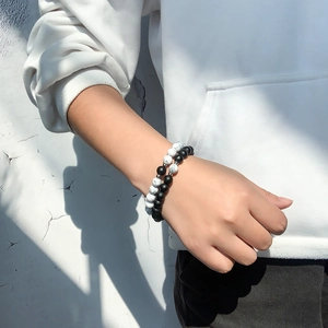 Detailed view of white turquoise and matte black stone bracelets worn on a wrist
