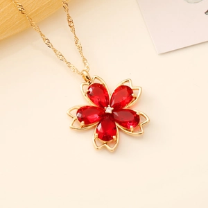 Detailed view of flower pendant necklace featuring red crystal petals and golden chain