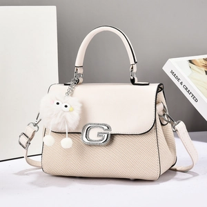 Beige woven crossbody bag with silver G buckle and plush charm on white background