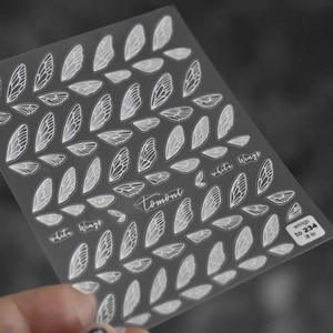 Macro shot of 5D white wing nail art stickers with translucent texture and fine lines
