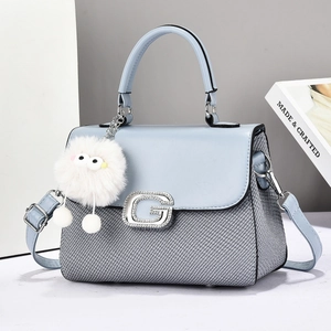 Close-up of light blue leather and woven fabric crossbody bag with silver G buckle and fur ball