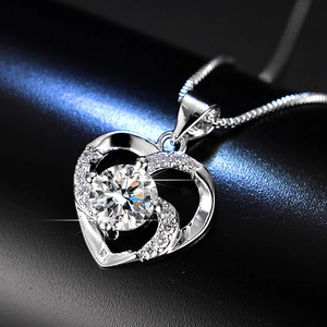 Macro detail of silver heart necklace with a brilliant round moissanite and pave stones