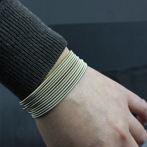Detail of layered gold and silver stainless steel coil bracelets on a model wrist