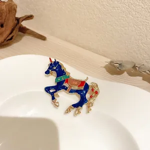 Vintage style enamel carousel horse brooch with blue unicorn design on white ceramic plate