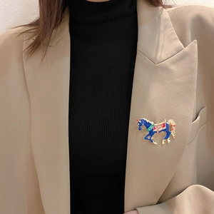 Close-up of blue enamel unicorn brooch pinned on a beige blazer lapel for styling