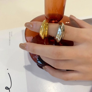Gepolijste gouden en zilveren ringenset gedragen op hand met artistiek glasdecoratie