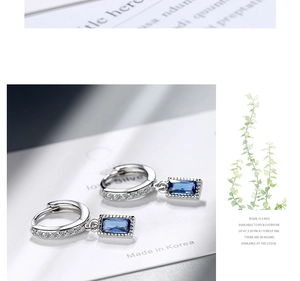 Macro shot of silver hoop earrings featuring blue baguette-cut stones and cubic zirconia