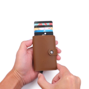 Brown leather popup card holder with aluminum shell showing automatic card ejection mechanism