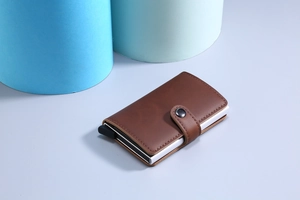 Detail view of the brown leather and aluminum pop-up card holder with push-button lever