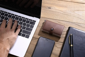 Brown PU leather card holder on a wooden desk with a laptop in a business setting