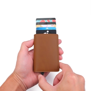 Detail of hand operating brown leather RFID wallet with pop-up card mechanism