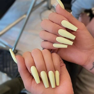 Macro shot of long coffin shaped pale yellow matte press-on nails for women
