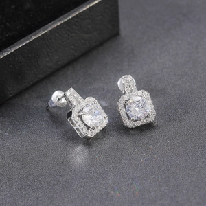 Macro shot of silver square halo stud earrings with brilliant zircon stones on black texture