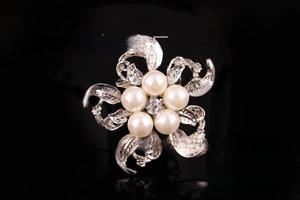 Dettaglio macro della spilla a fiore argento con perle bianche e cristallo di zircone