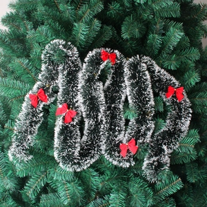Détail d'une guirlande de Noël vert foncé avec pointes blanches et cinq nœuds rouges