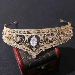 Detailed close-up of golden Baroque bridal crown with clear zircons on a rustic wood box