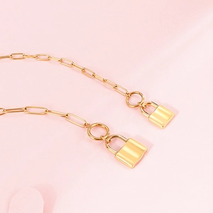 Gold-plated paperclip chain necklace with twin padlock pendants on pink background