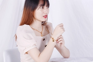 Detail of gold OT buckle titanium necklace and bracelet set with lock pendants on model