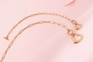 Detailed view of golden paperclip chain necklace with heart pendant and T-bar toggle clasp