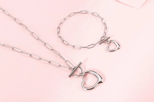 Detailed view of silver necklace and bracelet set with heart charms and OT toggle clasp