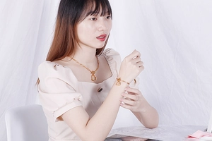 Detailed view of heart pendant necklace and bracelet set in gold on a model