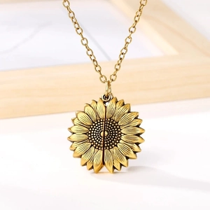 Detail of a vintage gold sunflower locket necklace with delicate engraved flower texture