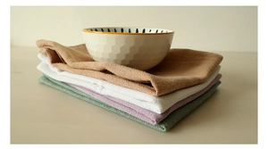 Macro detail of stacked cotton linen waffle napkins in neutral tones with ceramic bowl