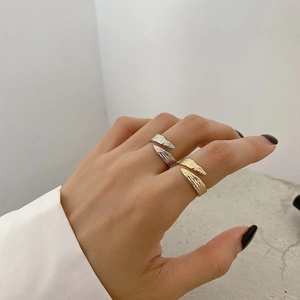 Detail of wave-textured 925 sterling silver rings in gold and silver finish on hand