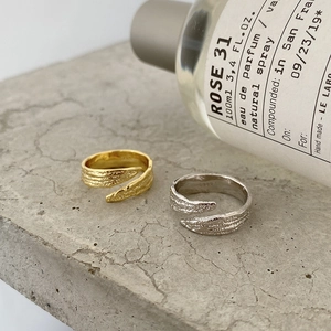 Detail shot of gold and silver textured S925 rings on industrial stone background