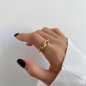 Detailed view of a gold-plated link ring worn on hand with a minimalist aesthetic