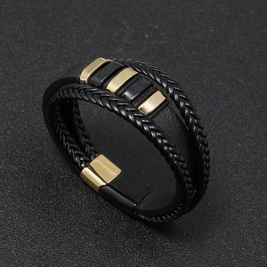 Detail of men's braided leather bracelet featuring black gold magnetic clasp and textures