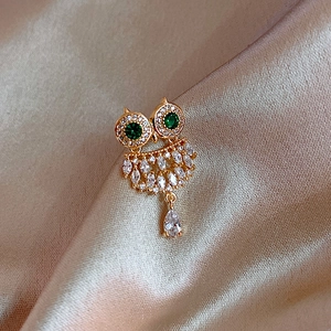 Elegant owl brooch with green eyes and crystal rhinestones on gold silk background