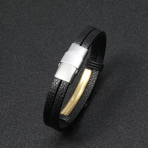 Detail of black double-layered leather bracelet with brushed steel clasp and gold accent